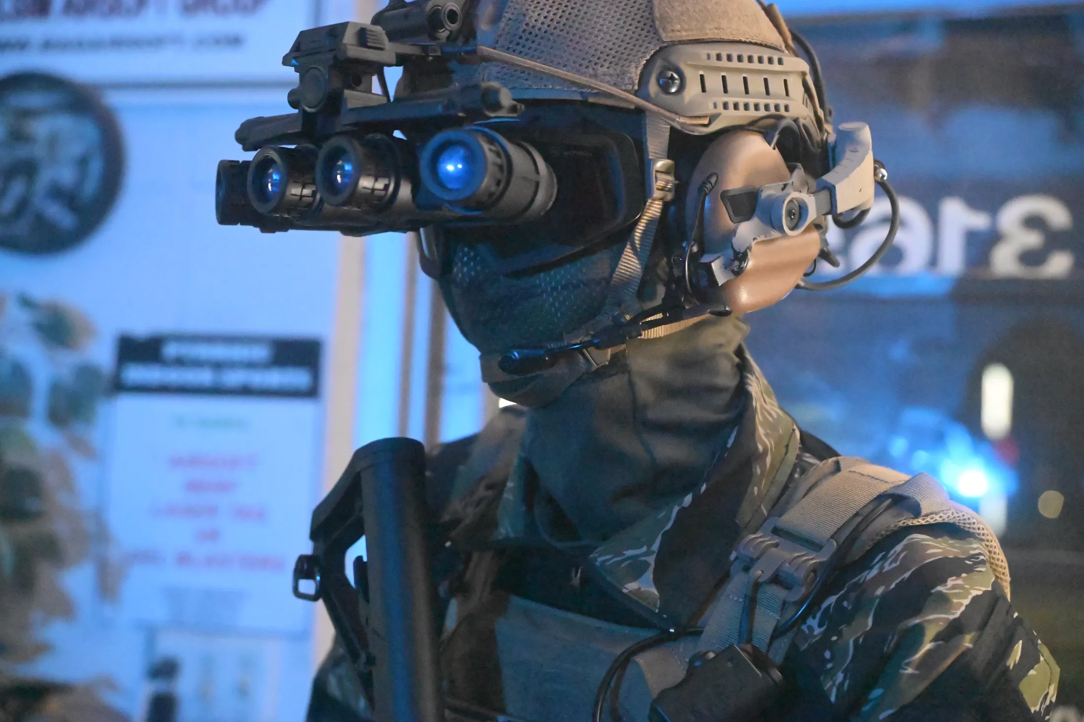 Commando in a helmet with four-tube night-vision goggles and a face mask inside the shop, from Rusty Rehl's Combat Sport Supply ad