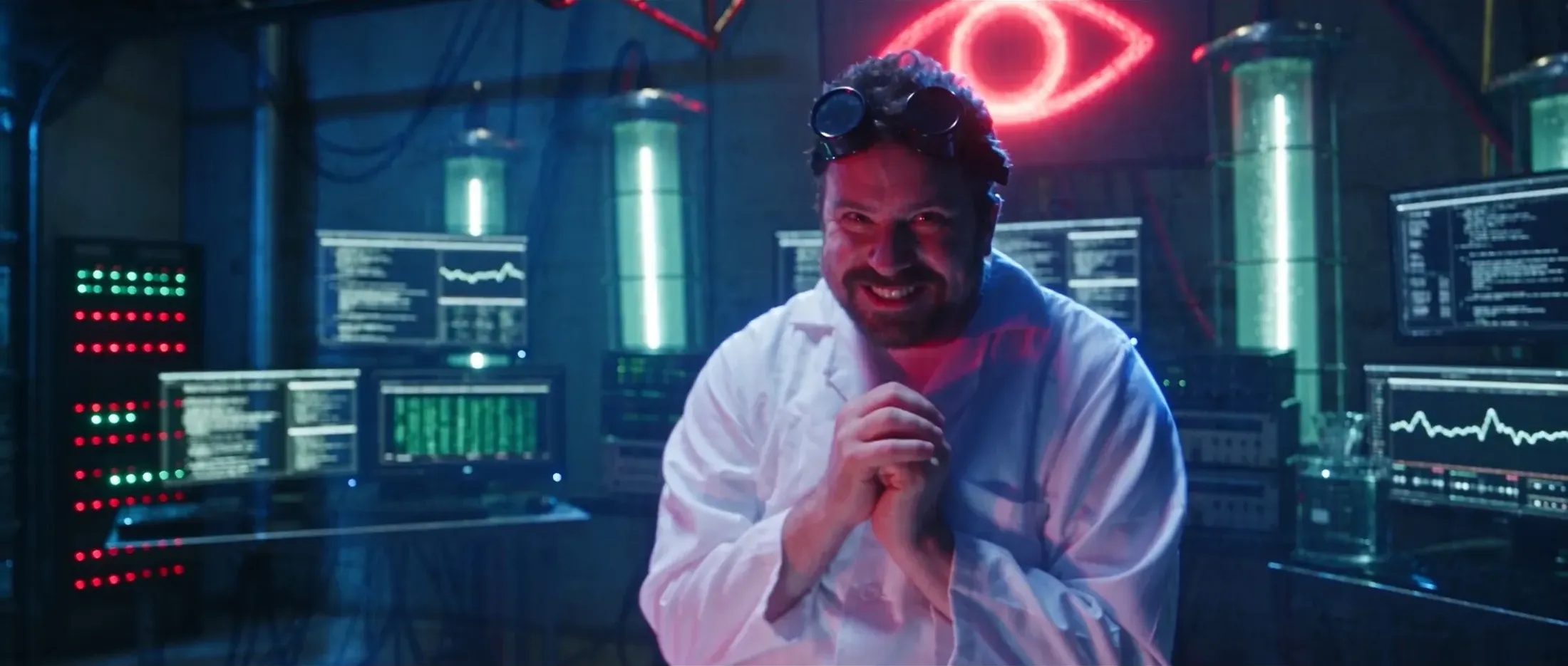 Mad scientist in a white lab coat and goggles under a red neon eye in a lab of glowing tubes and monitors, still from Rusty Rehl's ad for Combat Sport Supply