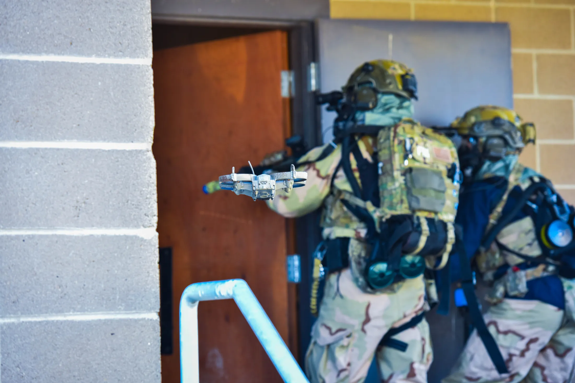 Small drone scouts a doorway ahead of an entry team in chemical protective gear during Exercise Hellgate in Idaho, photo by Rusty Rehl