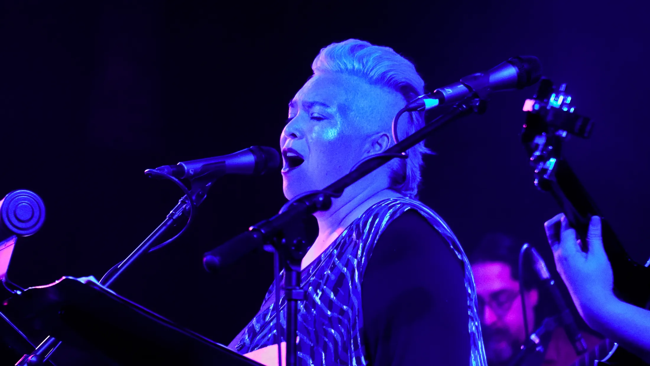 Singer with eyes closed in blue stage light, Boise, Idaho concert photo by Rusty Rehl