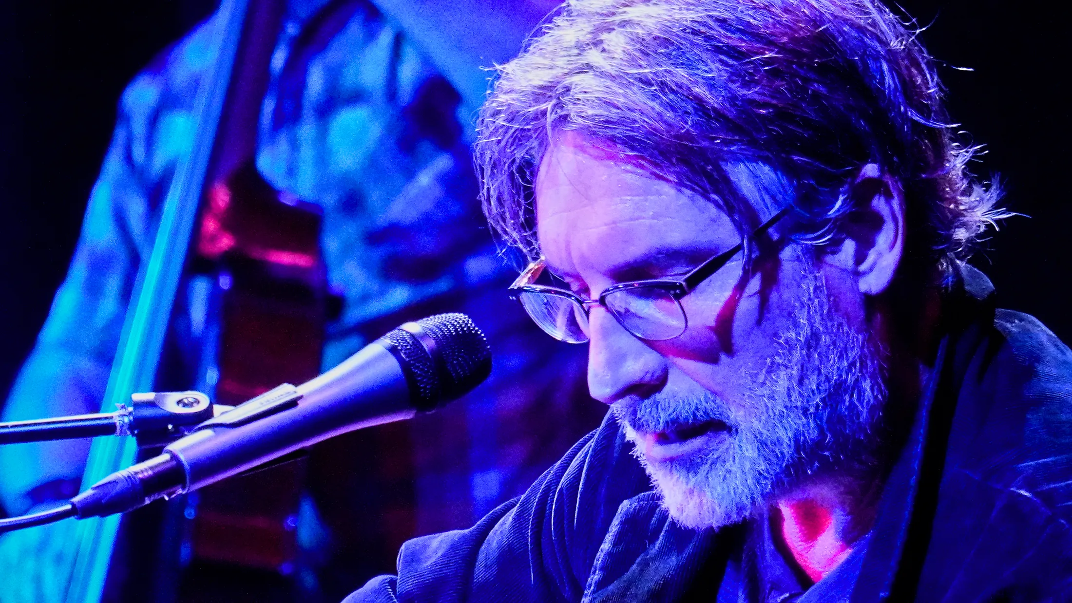 Close portrait of Martin Daniels at the microphone in blue light, Boise, Idaho concert photo by Rusty Rehl