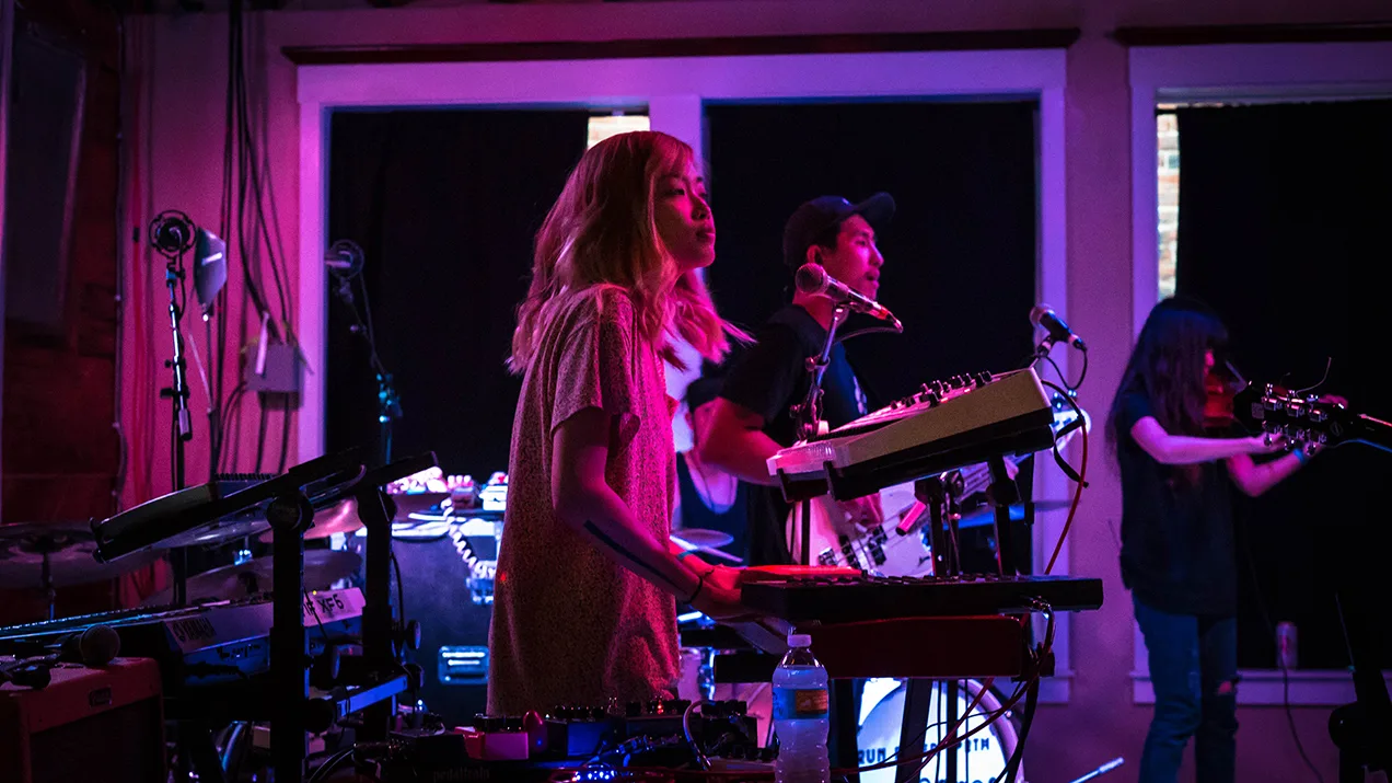 Run River North keyboardist in pink stage light with the band behind her, concert photo by Rusty Rehl