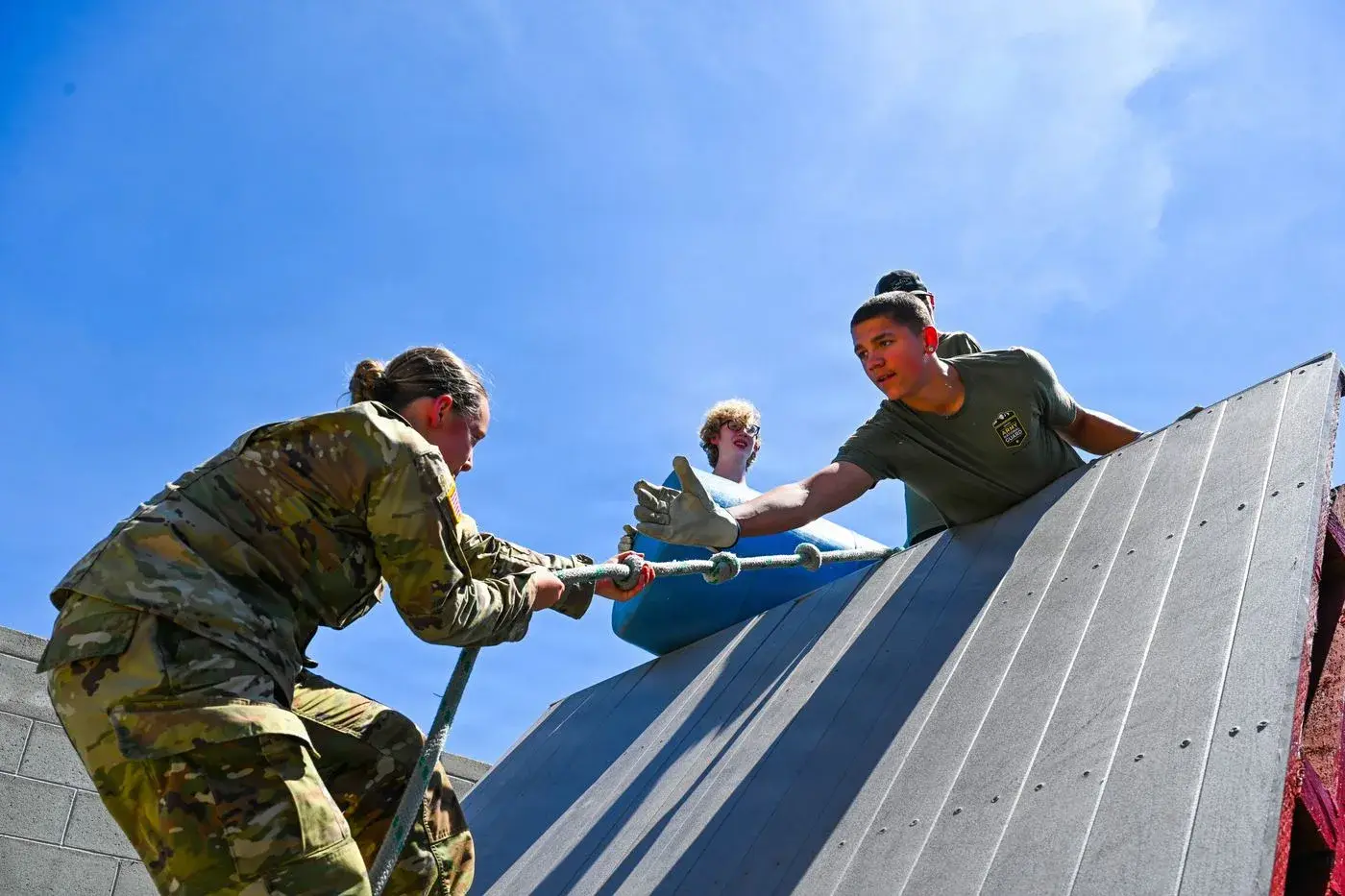 Idaho National Guard soldiers help each other up a rope wall on an obstacle course, photo by Rusty Rehl